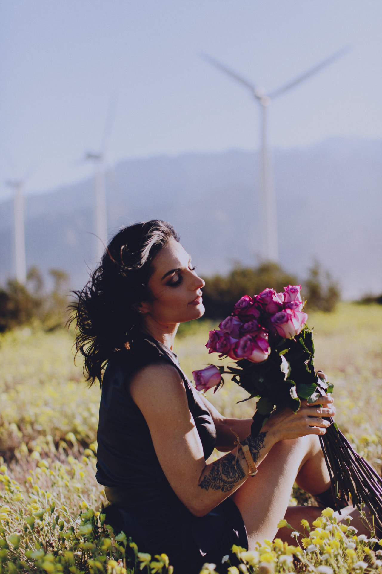 Woman sitting in a wildflower field holding roses at golden hour